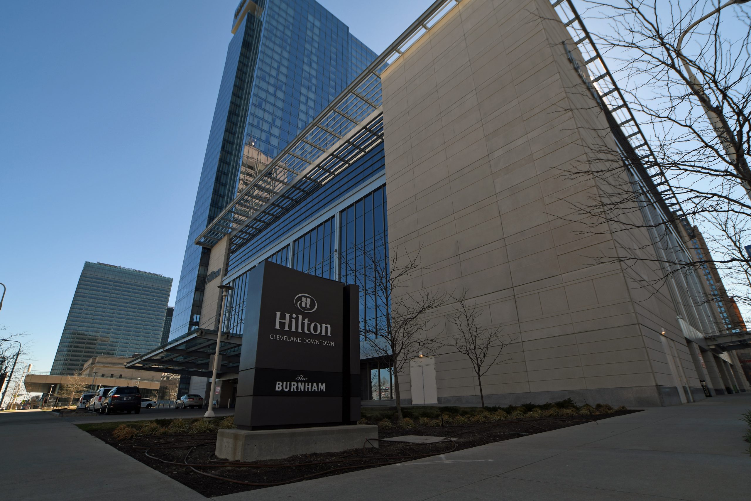 Exterior of Hilton hotel. The left side of the hotel's exterior is mostly glass and is very tall, while the right side is shorter and a combination of glass and then concrete.