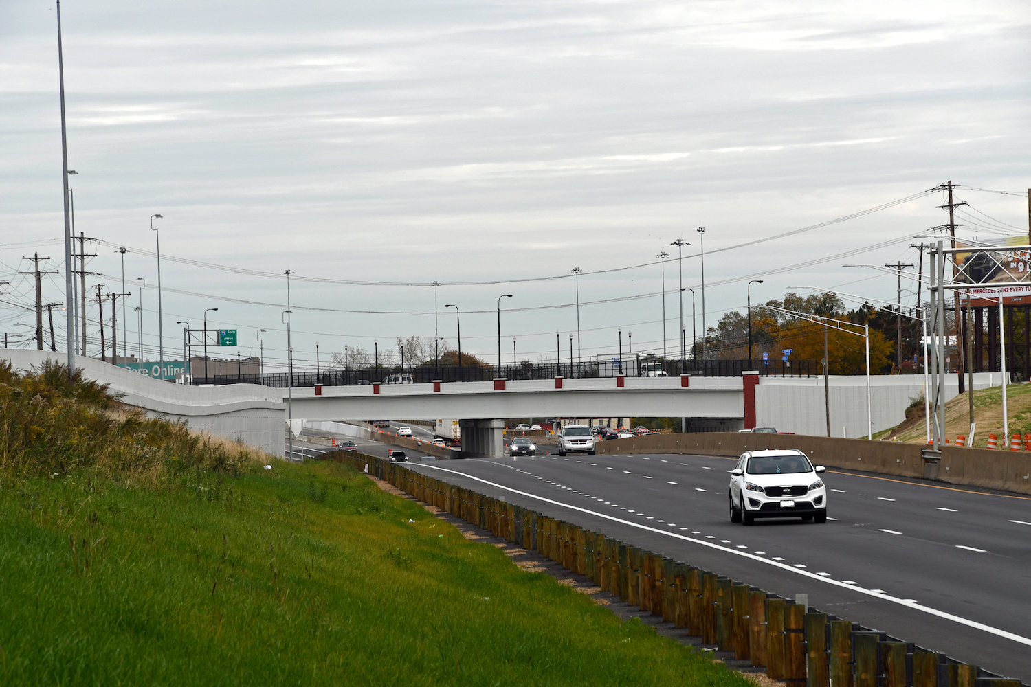 White bridge, with red brick accents over multiple lane highway with several cars.