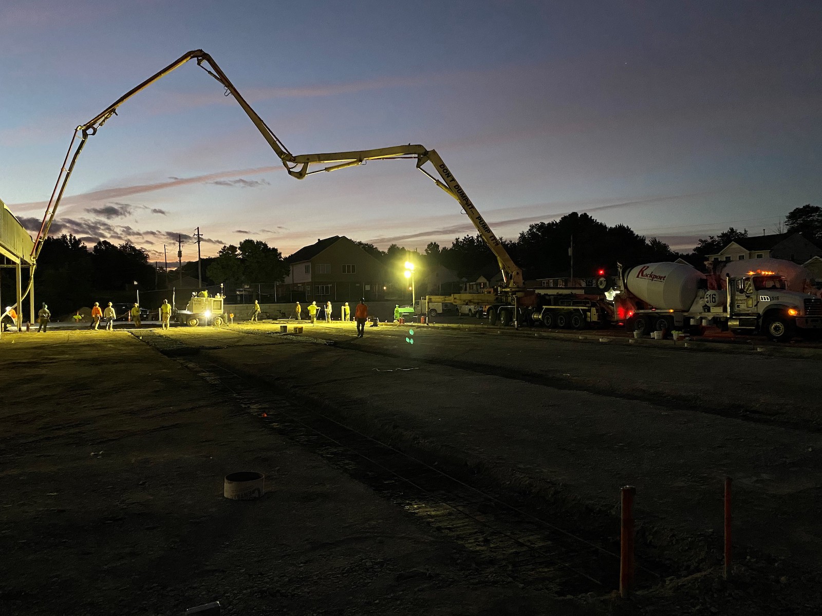 Construction workers continue to pour concrete as the sun sets.